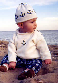 Baby on the beach wearing a Seashore Ivory Anchor Sweater